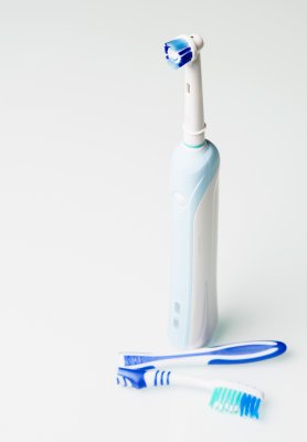 Electric toothbrush behind a broken manual toothbrush